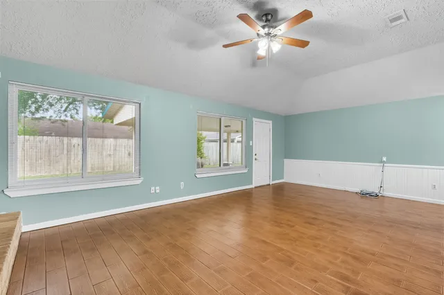 a view of an empty room with chandelier fan and a window