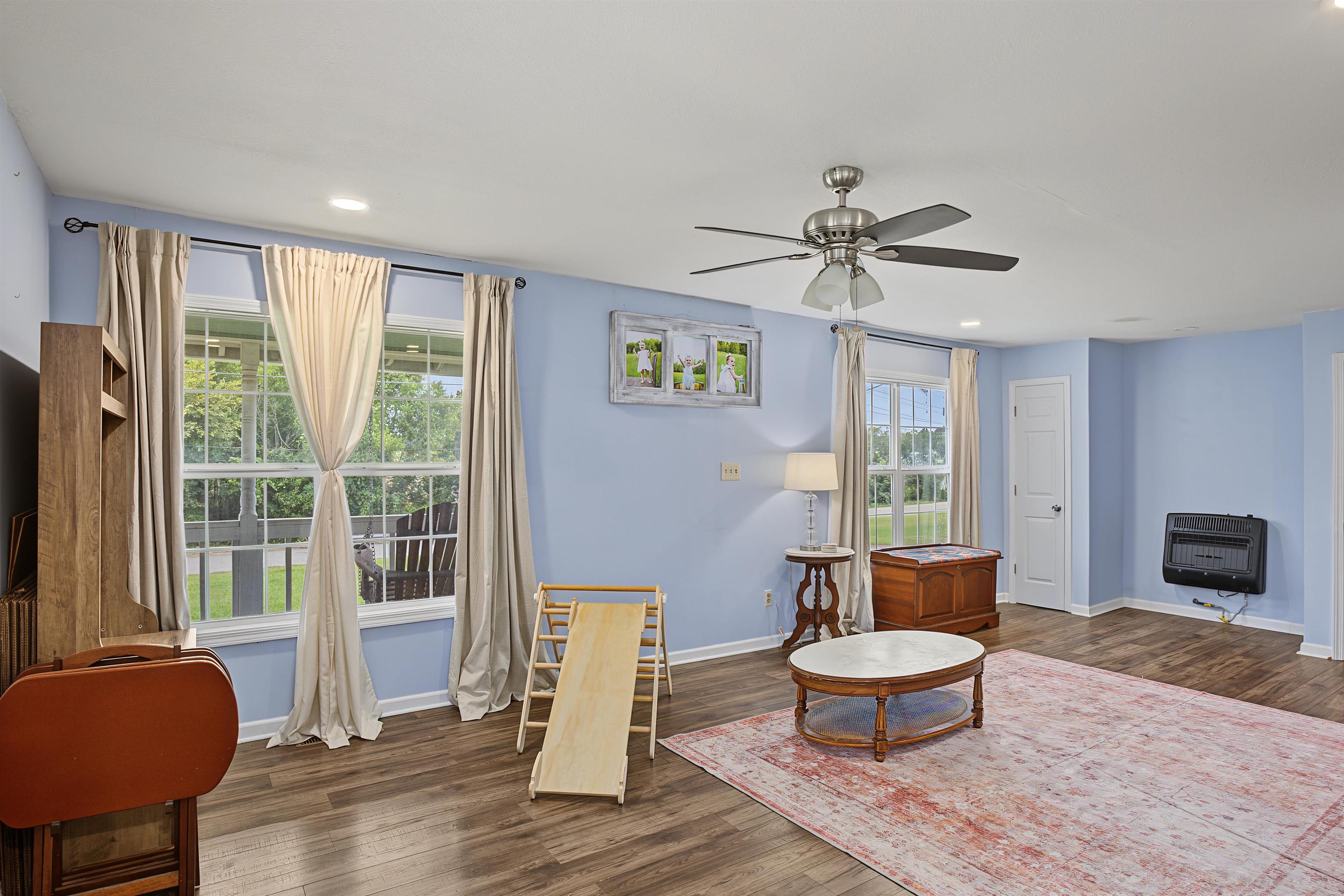 246 Cherryville Road Bells, TN 38006 - Photo 8 of 31 Recessed ceiling lighting, wood-finish flooring, ceiling fan with integrated lighting, multiple windows, and a wall-mounted heating unit