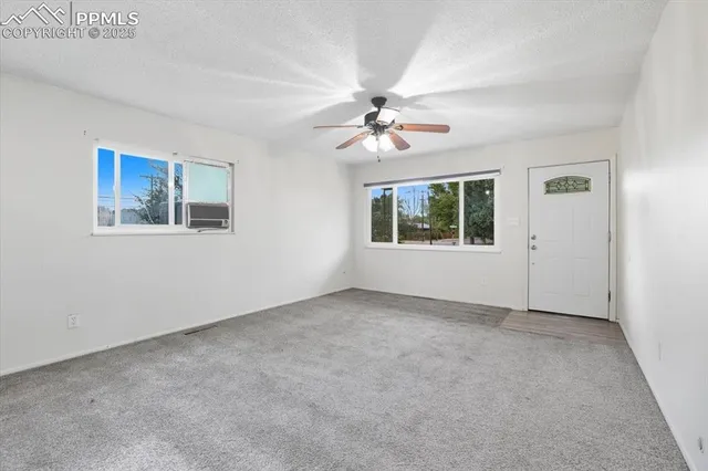 an empty room with windows and fan