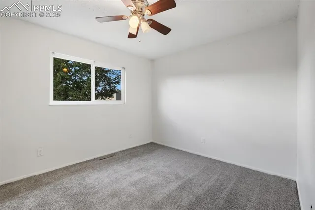 an empty room with a window and a fan