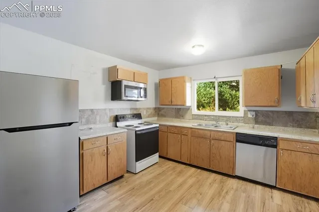 a kitchen with stainless steel appliances granite countertop a stove a sink dishwasher a refrigerator white cabinets and wooden floor