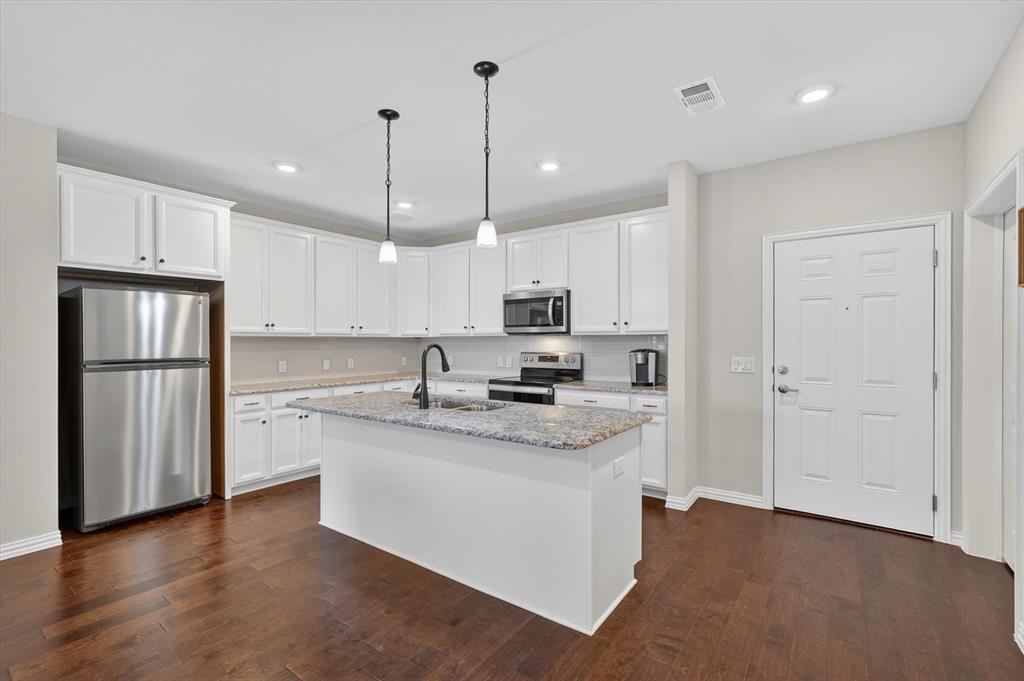 651 Watters Road, Unit 5305 Allen, TX 75013 - Photo 8 of 40 a kitchen with stainless steel appliances granite countertop a refrigerator a sink dishwasher a stove and white cabinets with wooden floor