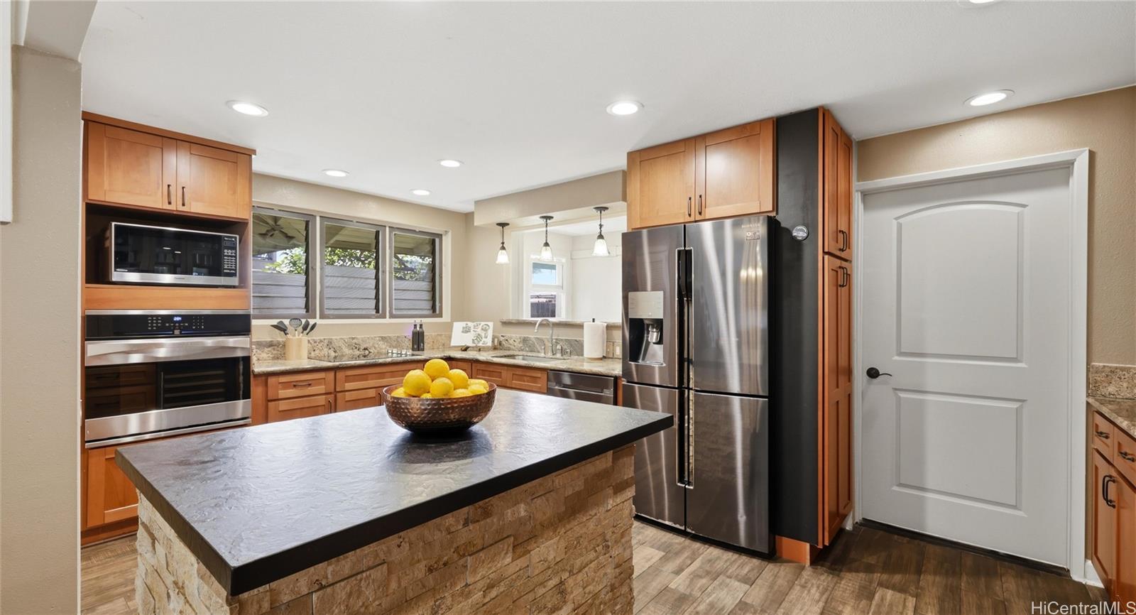 91-779 Fort Weaver Road Ewa Beach, HI 96706 - Photo 10 of 25 Chef's kitchen featuring stainless steel appliances, granite countertops, and a stone-accented center island.