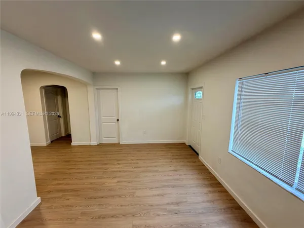 a view of an empty room with wooden floor and a window