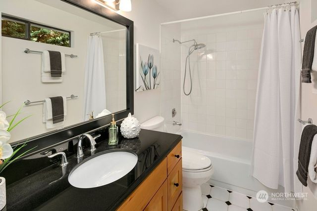 a bathroom with a granite countertop sink toilet a mirror a bathtub and shower