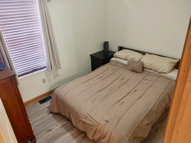 a bedroom with a bed and wooden floor