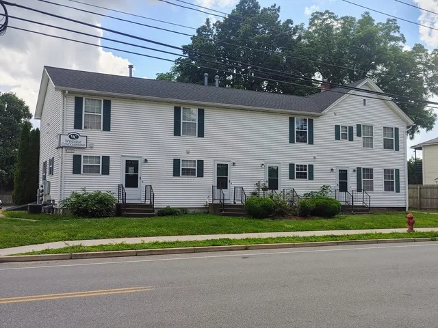a view of a white house with a yard and plants