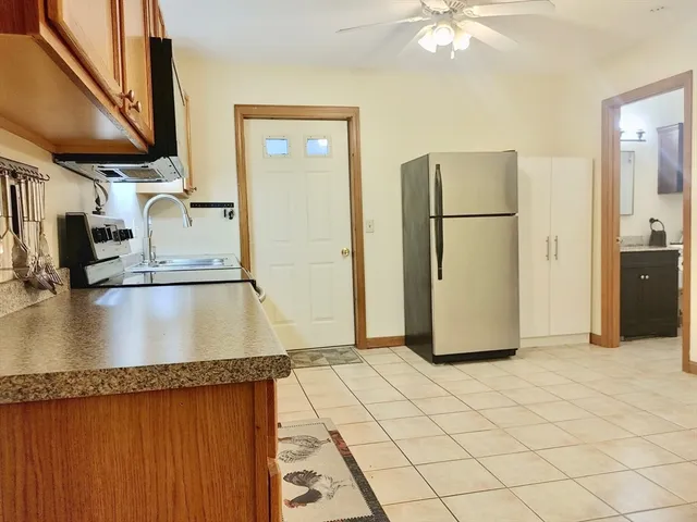 a kitchen with granite countertop a refrigerator a stove and a sink with wooden floor