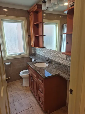 a bathroom with a granite countertop toilet sink and mirror