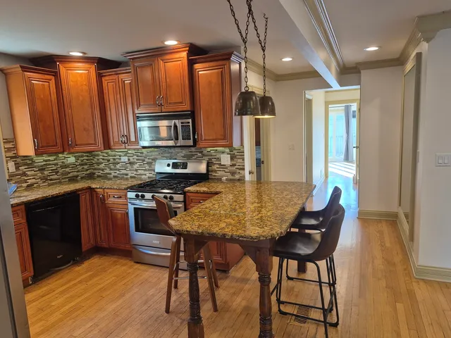 a kitchen with stainless steel appliances granite countertop wooden cabinets a stove top oven a sink and dishwasher
