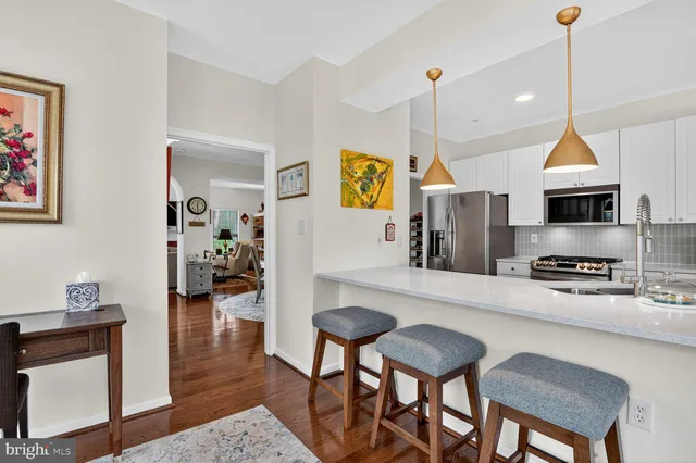 a kitchen with stainless steel appliances kitchen island granite countertop a table chairs and a refrigerator