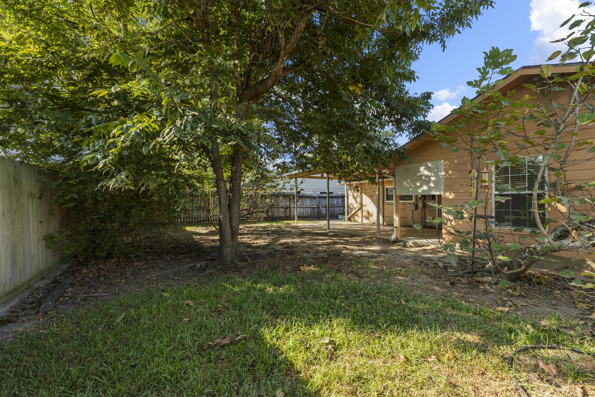 23826 Lestergate Drive Spring, TX 77373 - Photo 33 of 45 Beyond the covered patio, the backyard opens beneath a canopy of mature trees, creating plenty of shade and space to enjoy the outdoors. Looking back toward the home, the yard feels closely connected to the patio—an inviting setup for play, pets, gardening, or simply spending an afternoon outside.