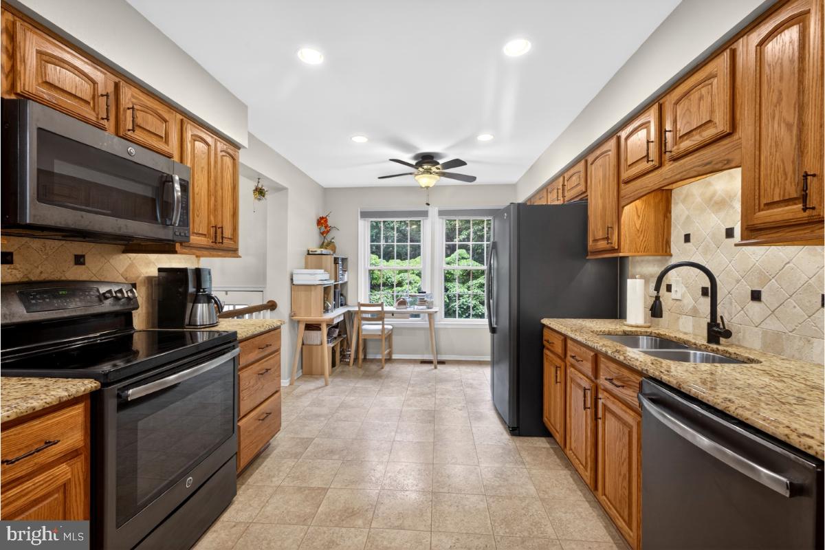 7347 Swan Point Way, Unit 122 Columbia, MD 21045 - Photo 12 of 54 a kitchen with stainless steel appliances granite countertop a stove top oven a sink dishwasher a dining table and chairs with wooden floor