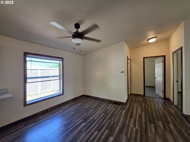 a view of a room with wooden floor a ceiling fan and windows