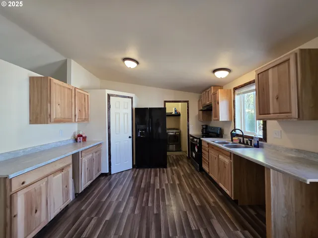 a kitchen with sink a refrigerator and wooden cabinets