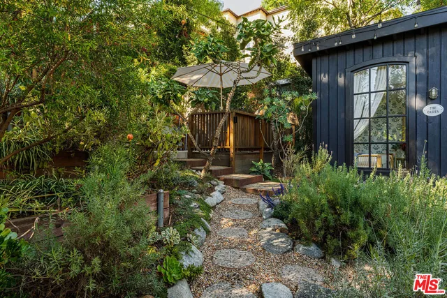 a view of a pathway of a house with a small yard plants and large tree