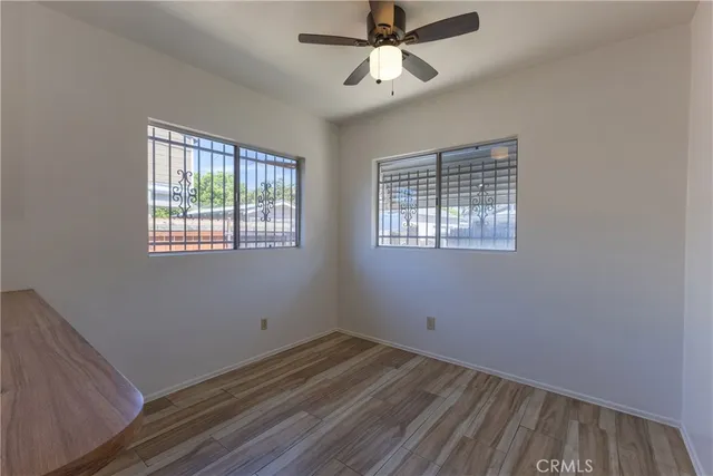a view of empty room with wooden floor and fan