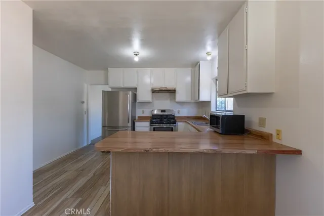 a kitchen with stainless steel appliances granite countertop a stove a sink a refrigerator white cabinets and a granite counter top