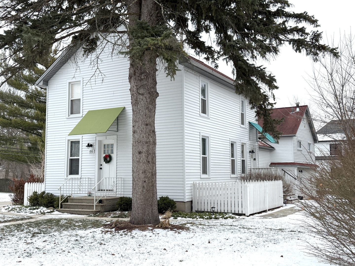 a front view of a house with a tree