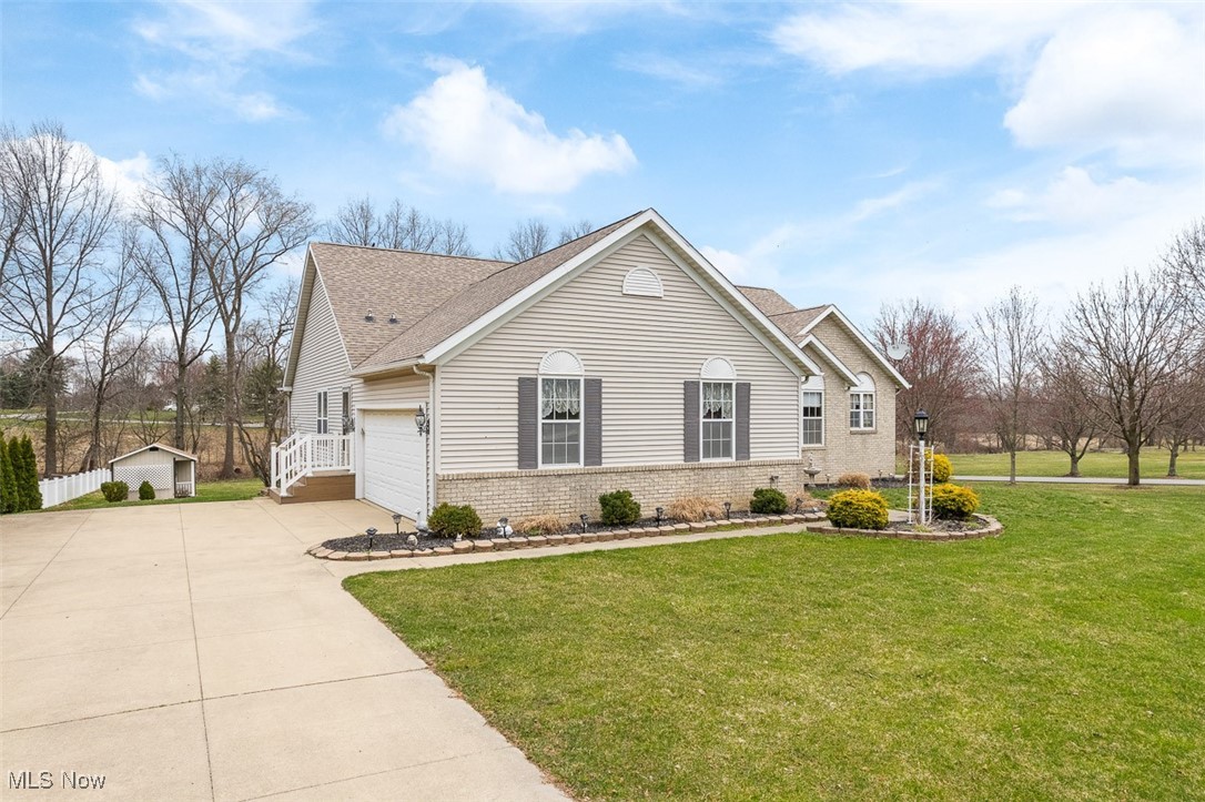 2271 Graybill Road Uniontown, OH 44685 - Photo 41 of 44 View of front of home featuring a shingled roof, an attached garage, concrete driveway, brick siding, and a front lawn