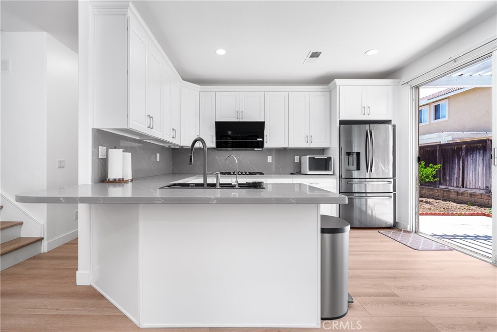 7358 Freedom Rancho Cucamonga, CA 91730 - Photo 15 of 34 a kitchen with stainless steel appliances granite countertop a stove top oven a sink a refrigerator and white cabinets with wooden floor