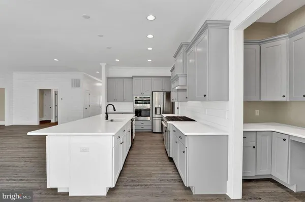 a large white kitchen with lots of counter space sink and stainless steel appliances