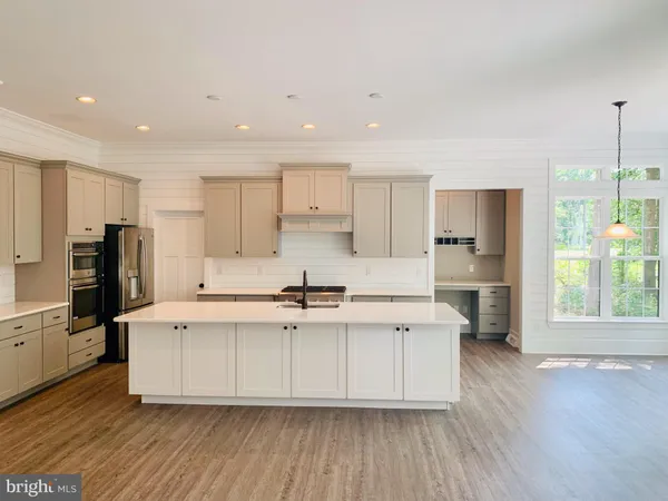 a kitchen with stainless steel appliances a stove top oven a refrigerator a sink and white cabinets with wooden floor