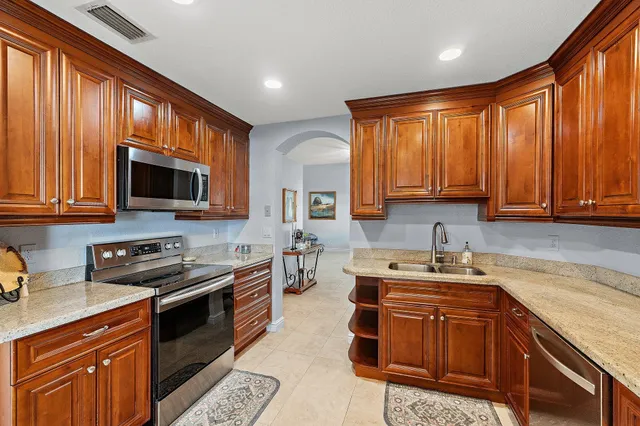 a kitchen with stainless steel appliances granite countertop wooden cabinets a stove top oven a sink and dishwasher