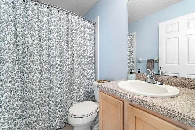 a bathroom with a granite countertop sink toilet and a mirror