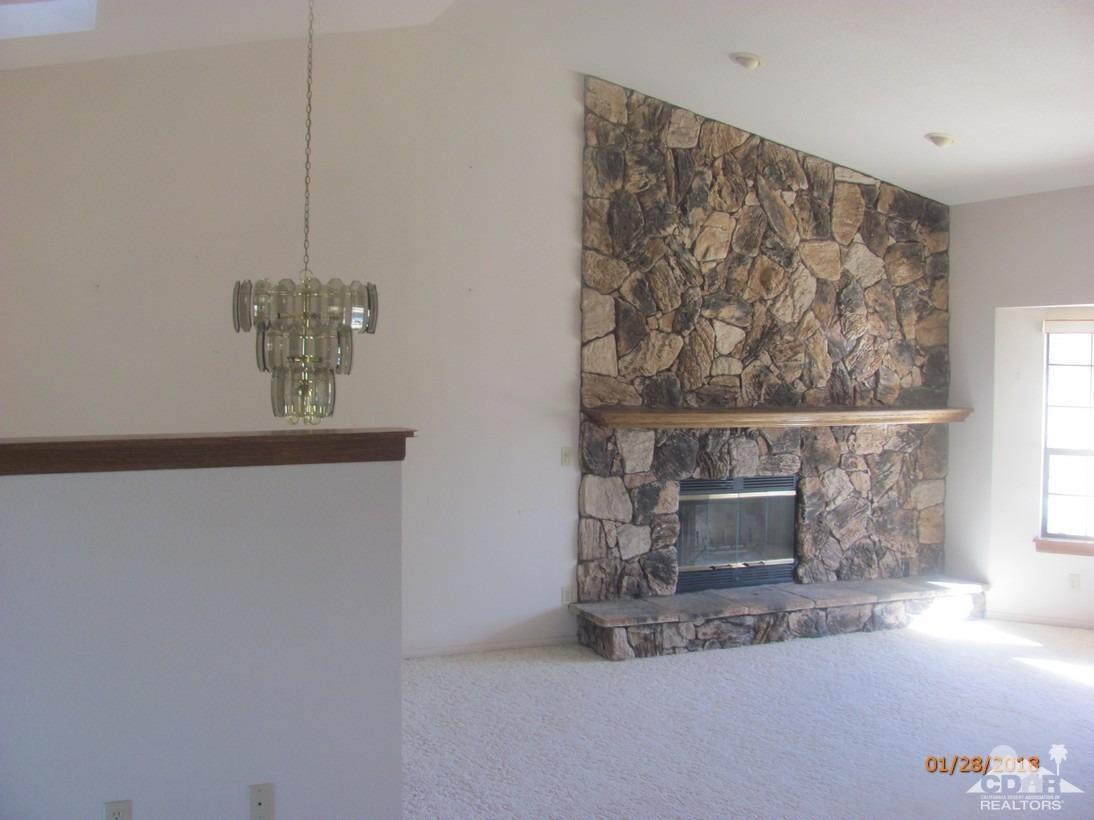 7078 Cascade Road Joshua Tree, CA 92252 - Photo 6 of 21 a room with a fireplace and a chandelier
