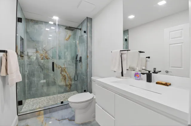 a bathroom with a shower sink vanity mirror and toilet