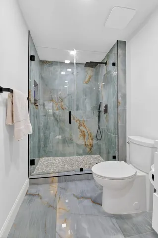 a bathroom with a granite countertop toilet a shower and a sink