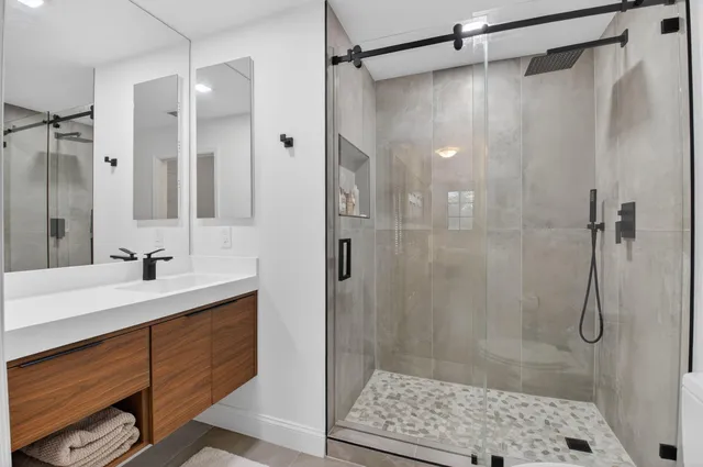 a bathroom with a sink shower and a mirror