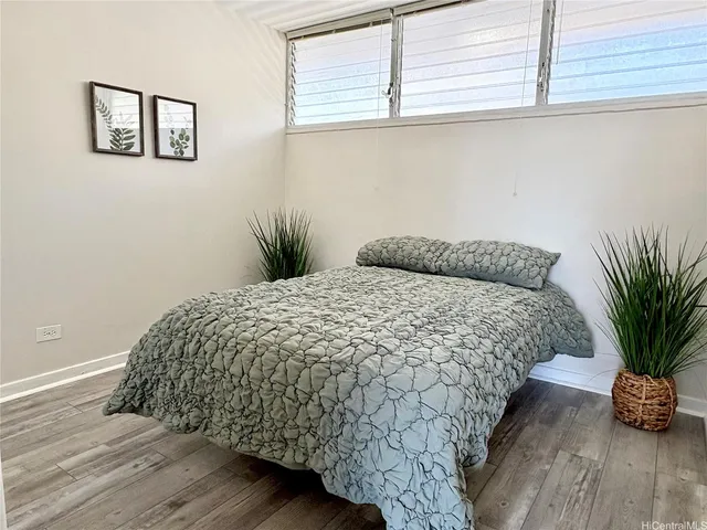 a bed sitting in a bedroom next to a window and a potted plant