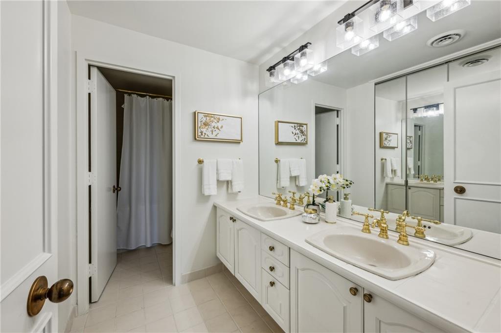 2660 Peachtree Road Northwest, Unit 23A Atlanta, GA 30305 - Photo 38 of 56 a bathroom with double vanity sinks a vanity a mirror and shower