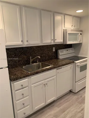 a kitchen with granite countertop white cabinets and white appliances
