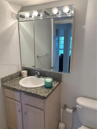 a bathroom with a granite countertop sink a toilet and a mirror