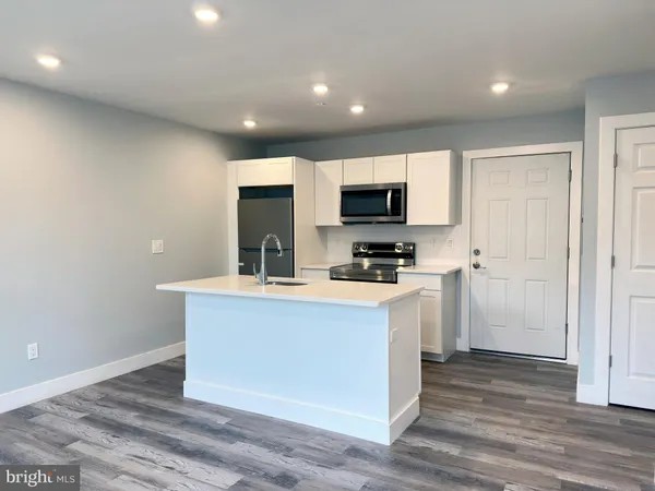 a kitchen with sink a microwave and cabinets
