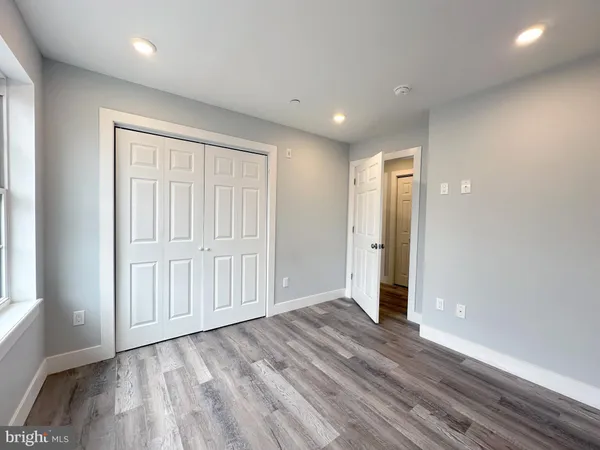 a view of an empty room with wooden floor and closet