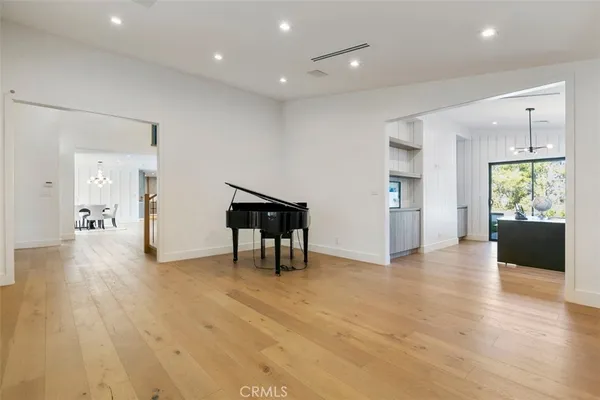 a view of an empty room with wooden floor and a kitchen