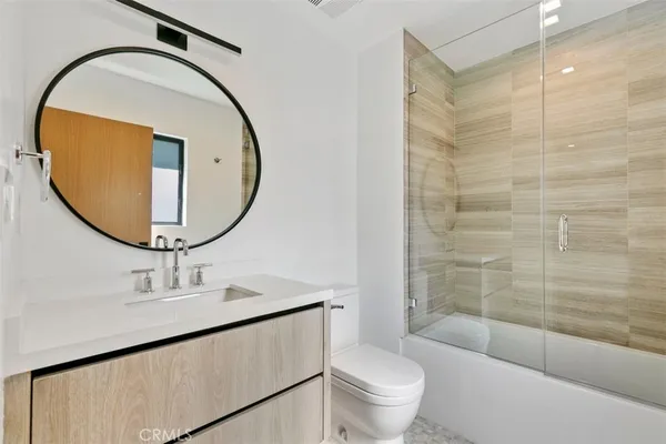 a bathroom with a toilet a sink a glass door a shower and a mirror