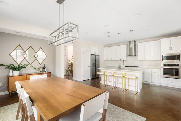 a open kitchen with stainless steel appliances granite countertop a stove refrigerator and white cabinets with wooden floor