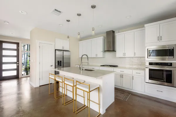 a kitchen with stainless steel appliances granite countertop a stove top oven a sink dishwasher and a refrigerator with wooden floor