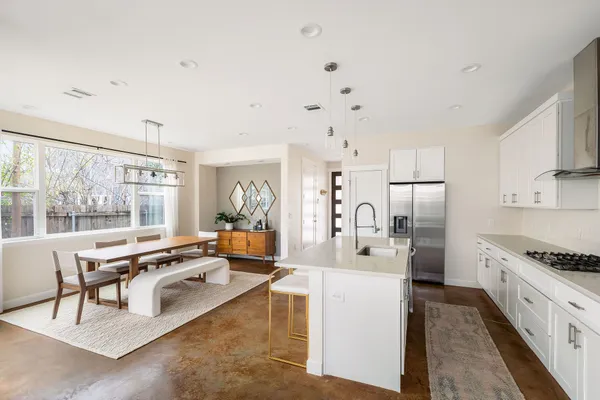 a large white kitchen with granite countertop a lot of counter space and stainless steel appliances
