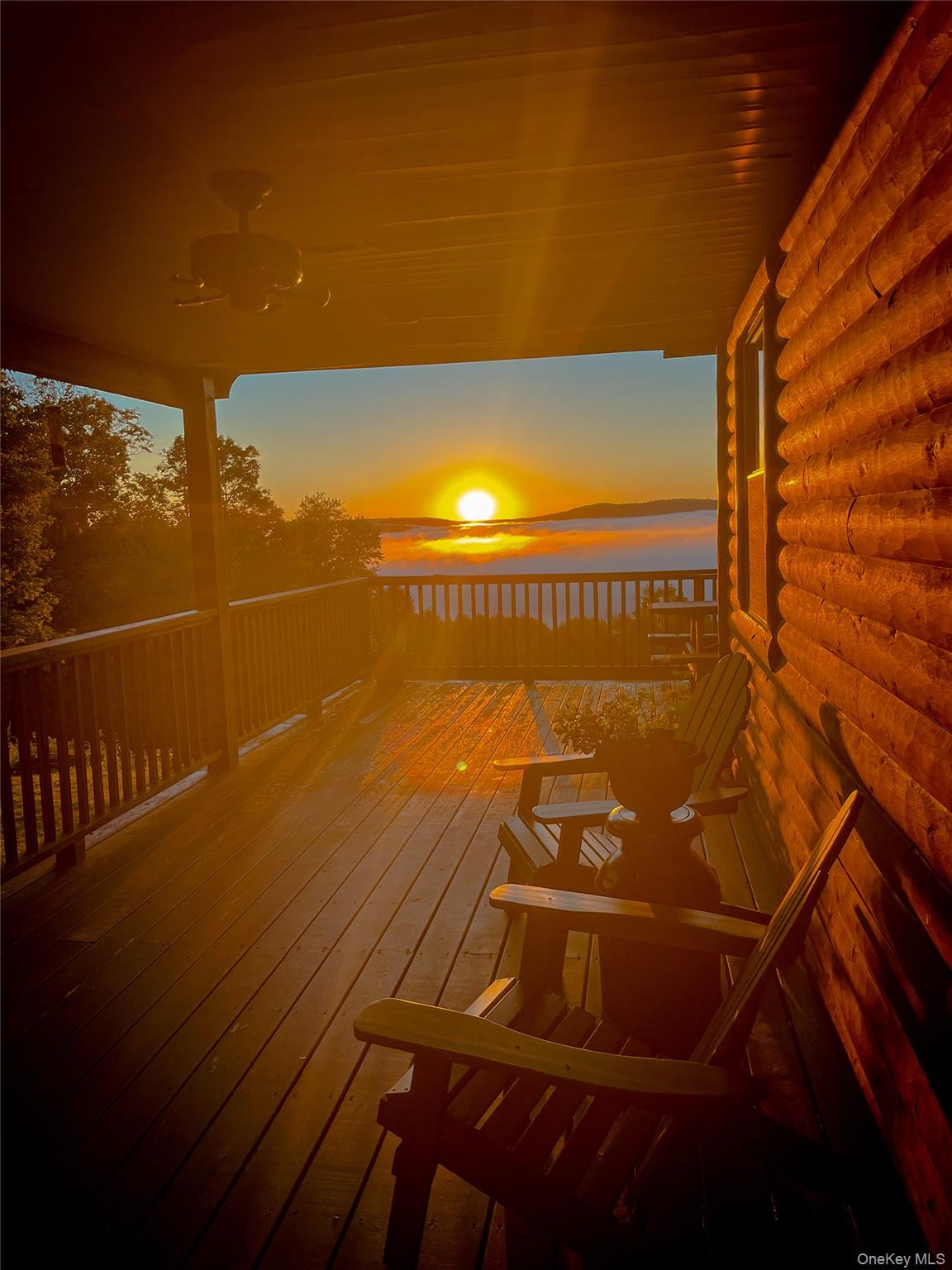 Expansive wooden deck with a log cabin exterior and a distant mountain and water scenery