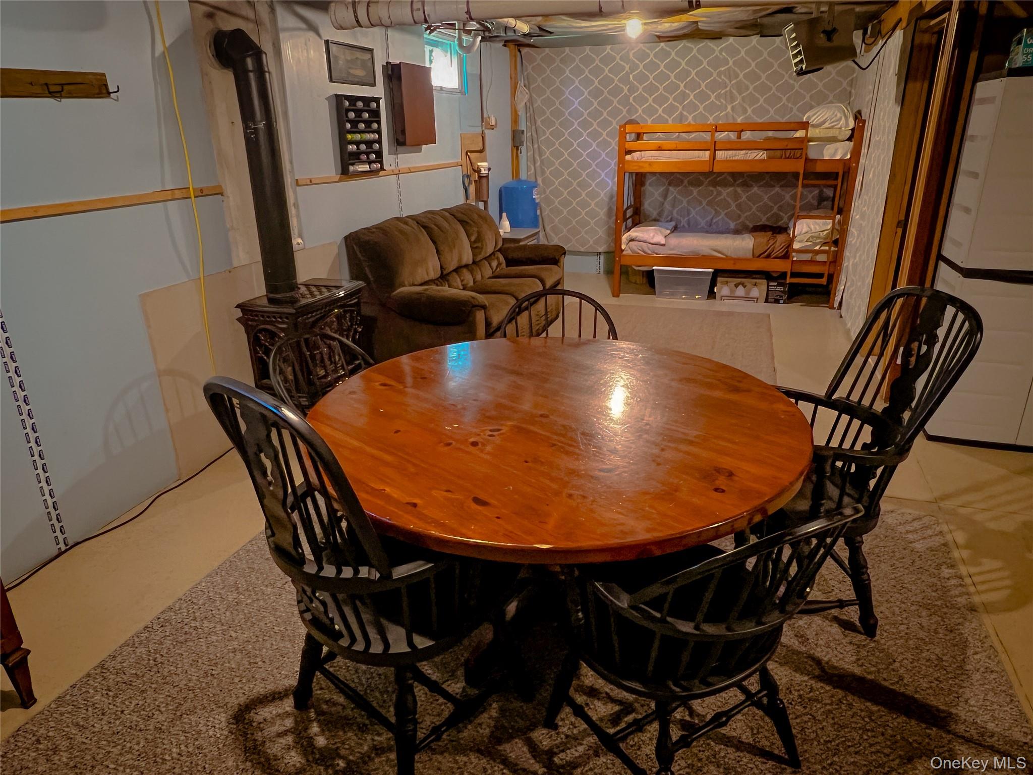 295 Emerald Heights Road Delancey, NY 13752 - Photo 12 of 30 Finished basement area featuring a round wood-finish table, a dark-toned wood stove, and light-toned walls
