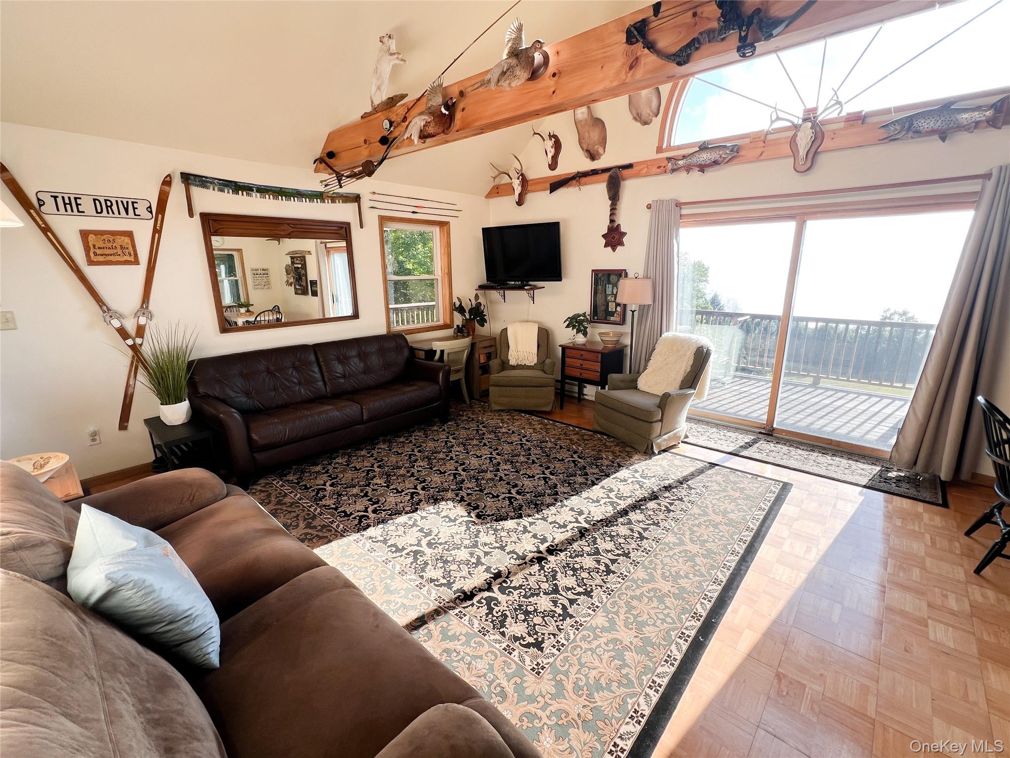 295 Emerald Heights Road Delancey, NY 13752 - Photo 21 of 30 Living area featuring a vaulted ceiling with exposed wood beams, a large arched transom window, and expansive sliding glass doors opening to a deck
