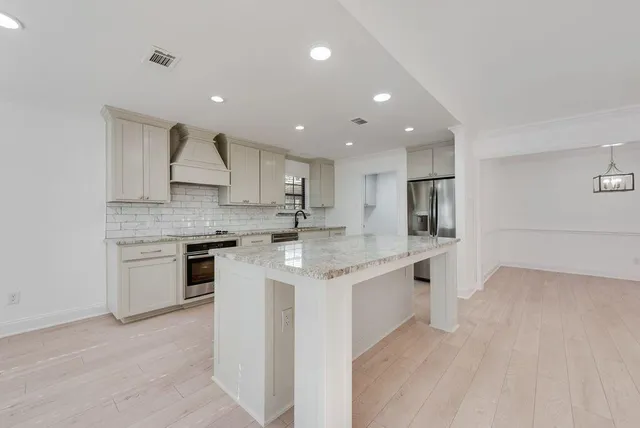 a kitchen with stainless steel appliances kitchen island granite countertop a stove a sink and a refrigerator