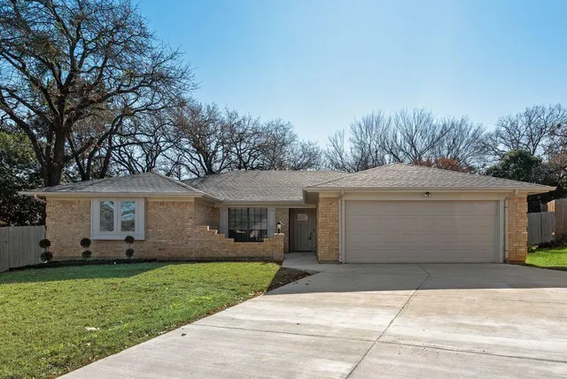 a view of a white house next to a yard and large trees
