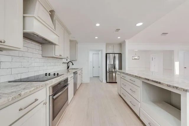 a large kitchen with stainless steel appliances granite countertop a lot of counter space and wooden floors